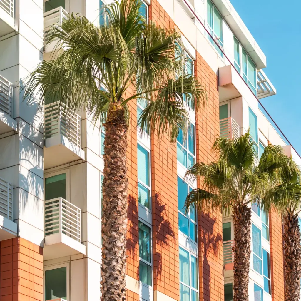 Modern apartment building with palm trees in a sunny coastal setting, representing the availability of cheap property Marbella for budget-friendly buyers and investors.