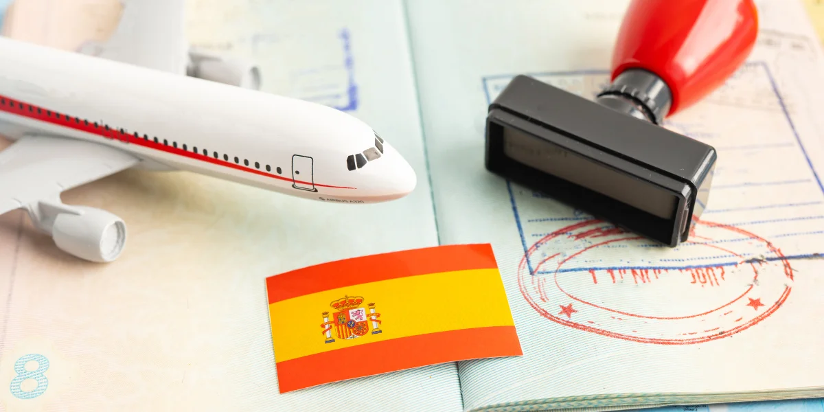Spanish flag, passport stamps, a travel stamp and an airplane model on a passport, illustrating information about the former Golden Visa in Spain and its current legal status.